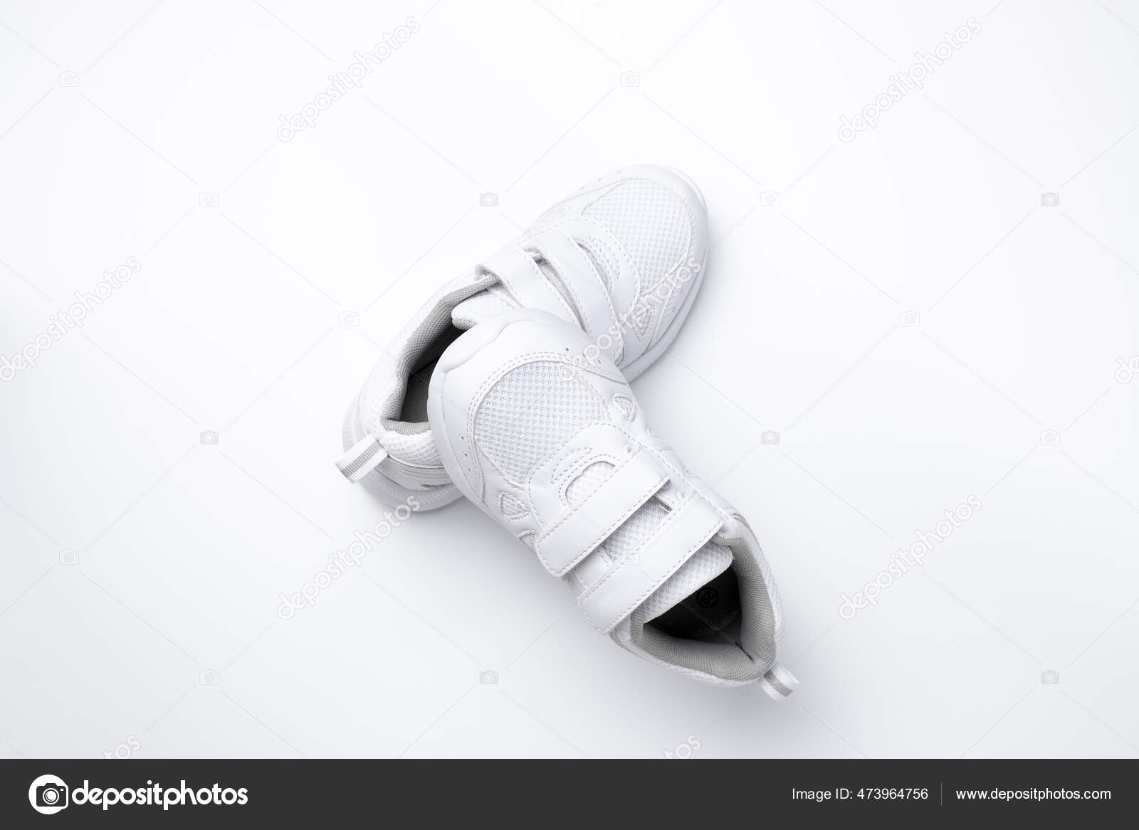 Zapatillas de deporte de niño blanco volador macro con cierres de velcro  aislado sobre un fondo azul con luz dura