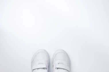 İki beyaz spor ayakkabısı, beyaz bir arkaplanda izole edilmiş metinler için boş alanı olan, merkezin alt kısmında kısmen yer alıyordu.