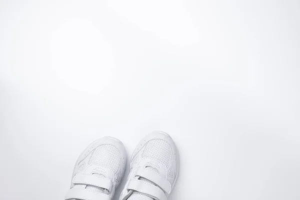 Vista dall'alto di due scarpe da corsa bianche parzialmente situate in basso con spazio libero per testo isolato su sfondo bianco — Foto Stock