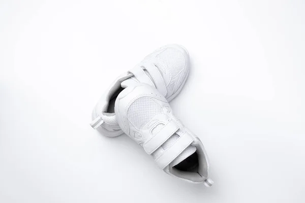 Vista superior en una pirámide de zapatillas de deporte de niño blanco, una zapatilla se encuentra en otra zapatilla aislada sobre un fondo blanco — Foto de Stock