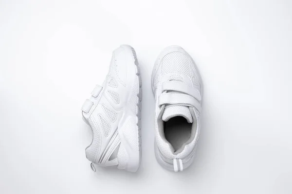 Bovenaanzicht twee witte unisex sneakers, één sneaker is aan de zijkant geïsoleerd op een witte achtergrond — Stockfoto