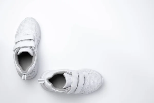Beyaz arka planda birbirine 90 derecelik açıyla bağlı iki beyaz unisex spor ayakkabısı yatıyordu. — Stok fotoğraf