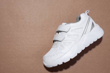 Makro düz bir beyaz çocuk ayakkabısı ve cırt cırtlı bağcıklar sert gölgeli kahverengi bir el işi kağıdının üzerinde yatıyordu.