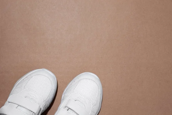 Mock up flat lay due sneakers bianche parzialmente collocate in basso al centro con spazio libero per testo isolato su fondo carta artigianale — Foto Stock