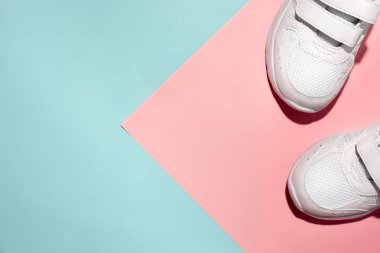 Üst görünüm köşedeki beyaz spor ayakkabıların üst kısımları hassas bir geometrik kağıt üzerinde pembe ve mavi arka plan sert gölgeler ile, metin alanı kopyalama
