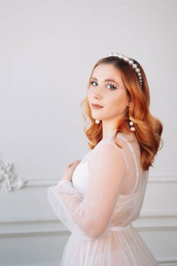 Beyaz şeffaf elbiseli masum kızıl saçlı bir kadının yarım yamalak portresi ya da parıltılı bir çerçevenin içinde gözüne yakın incilerden yapılmış bir pelerin.