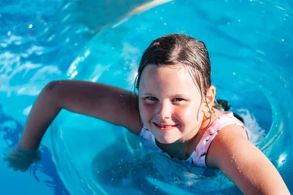 Pembe mayo giymiş bir kızın portresi şeffaf bir dairenin içinde parlak güneşli bir günde mavi bir havuzda ya da denizde yüzüyor. — Stok fotoğraf