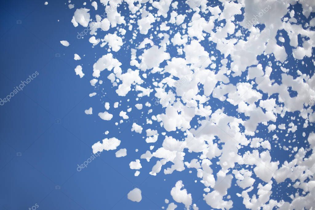 foam flakes from a foam pool party on the background of a blue summer sunny clear sky with copy space