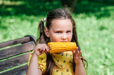 Bir çocuk bir mısır tanesidir. Sarı mısır ve parkta yürüyüş yapan sarı elbiseli bir çocuk. Çocuklar vejetaryenlik ve sağlıklı tatlılar