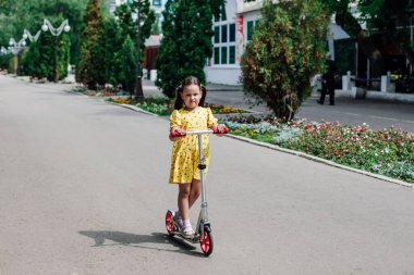 Bir kız mobilete biniyor, yaz günü motosikletle aile yürüyüşü yapıyor, sağlıklı bir yaşam tarzı ve eğlencesi var.