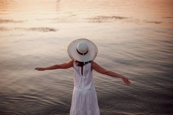 Eine entspannte Frau genießt die Sonne, die Freiheit und das Leben an einem schönen Strand bei Sonnenuntergang. Das Konzept von Urlaub, Freiheit, Glück, Vergnügen und Wohlbefinden — Stockfoto