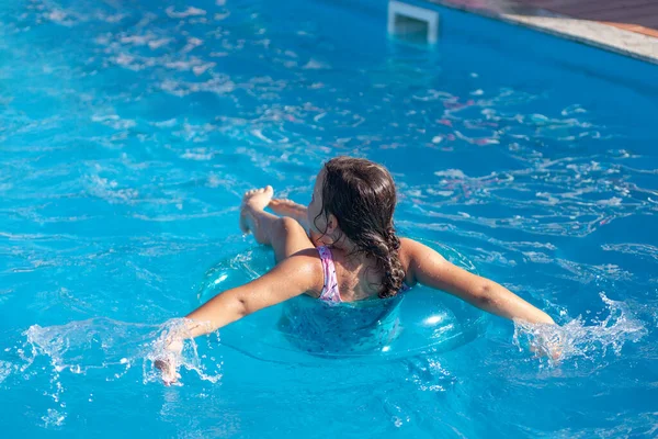 Lány lebeg egy felfújható kört a kék víz a medence, a koncepció a deperszonalizáció — Stock Fotó