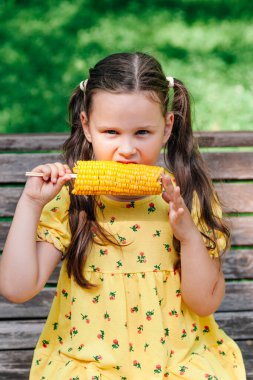 Tatlı kız, yaz barbeküsü sırasında bahçede kaynamış mısırdan hoşlanır.