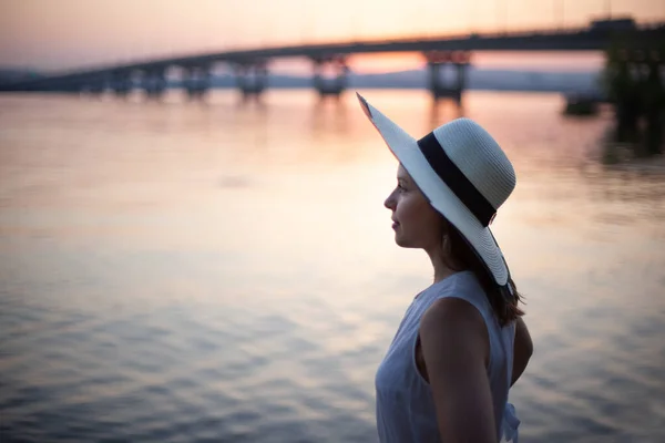 Profile portrait of a woman in a hat on a mini trip along the river at sunset — 图库照片