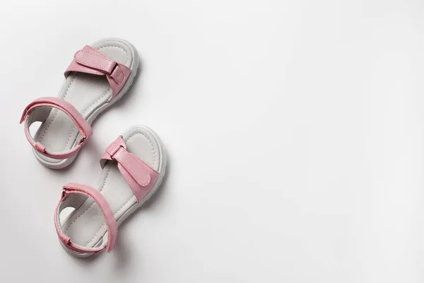 Pinkfarbene Kindersandalen aus glänzendem Leder mit Klettverschlüssen, flache weiße Sohlen isoliert auf weißem Hintergrund. Ein Paar modische Kindersandalen für einen bequemen Spaziergang. — Stockfoto