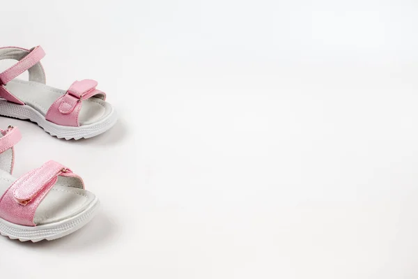 Růžové dětské sandály z lesklé kůže se suchými zipy, ploché bílé podrážky izolované na bílém pozadí. Pár módních dětských sandálů pro pohodlnou procházku. — Stock fotografie