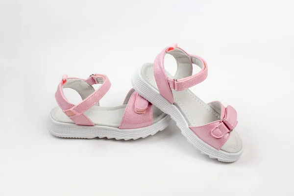 Sandálias infantis rosa feitas de couro brilhante com fechos de velcro, solas brancas planas isoladas em um fundo branco. Um par de sandálias infantis na moda para um passeio confortável. — Fotografia de Stock