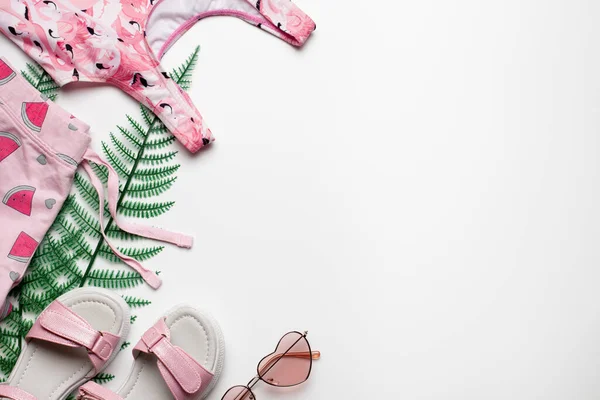 Strandmode Mädchen Kleidung und Accessoires auf weißem Hintergrund mit tropischen Palmblättern. Flache Lage, Draufsicht — Stockfoto