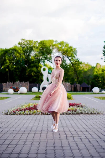 夏に公園で踊るピンク色の絹のドレスを着たバレリーナ都会の風景の中でバレエ — ストック写真