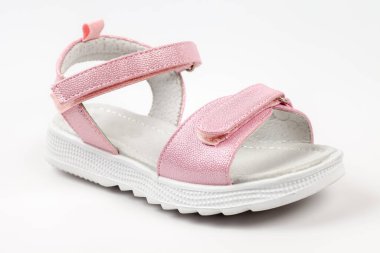 Cırt cırtlı bağcıklı parlak deriden yapılmış pembe çocuk sandaletleri, beyaz arka planda izole edilmiş düz beyaz tabanlar. Rahat bir yürüyüş için bir çift şık çocuk sandaleti..