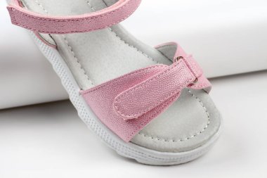 Pembe izole sandaletler. Beyaz tabanlı pembe sandaletler ve beyaz arka planda izole edilmiş cırt cırtlı bağcıklar. Çocuklar için şık çocuk ayakkabıları.