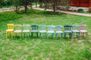 Arka bahçede parlak renklerle boyanmış tahta Viyana sandalyelerinin üst görüntüsü, eski mobilyaların restorasyonu için çevre dostu atölye