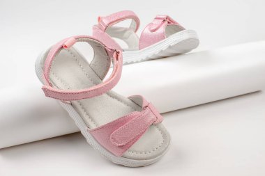 Pembe izole sandaletler. Beyaz tabanlı pembe sandaletler ve beyaz arka planda izole edilmiş cırt cırtlı bağcıklar. Çocuklar için şık çocuk ayakkabıları.