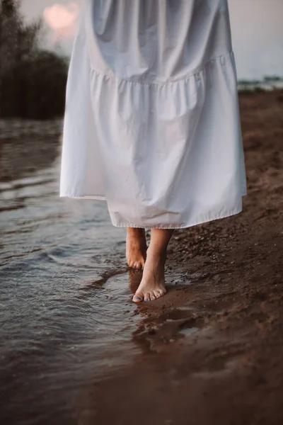 夏天浪漫散步的概念。日落时沿着海滨散步的女人赤脚 — 图库照片