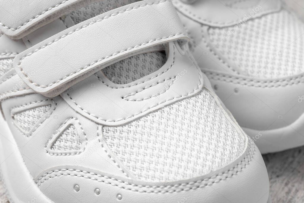 Macro photography of white sneakers. Two white childrens shoes with Velcro fasteners for the convenience of childrens shoes, top view