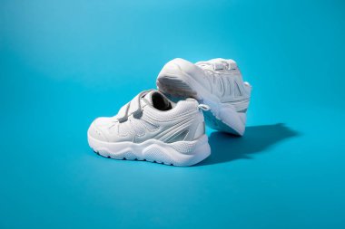 Mavi kağıt arka planda cırt cırt cırtlı iki beyaz çocuğun dengeli kompozisyonu, bir spor ayakkabısı diğerinin üzerinde duruyor.