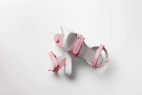 Pinkfarbene Kindersandalen aus glänzendem Leder mit Klettverschlüssen, flache weiße Sohlen isoliert auf weißem Hintergrund. Ein Paar modische Kindersandalen für einen bequemen Spaziergang. — Stockfoto