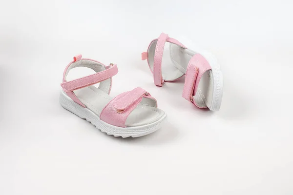 Pinkfarbene Kindersandalen aus glänzendem Leder mit Klettverschlüssen, flache weiße Sohlen isoliert auf weißem Hintergrund. Ein Paar modische Kindersandalen für einen bequemen Spaziergang. — Stockfoto