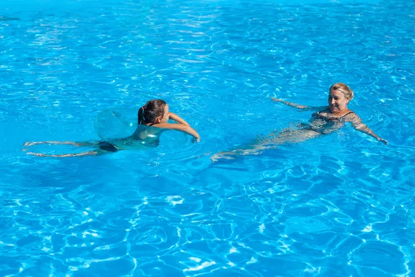 Nagymama és unokája a medencében. Egy fiatal nyugdíjas és egy lány úszkálnak a medence hideg vizében egy forró nyári napon egy családi kiránduláson. — Stock Fotó