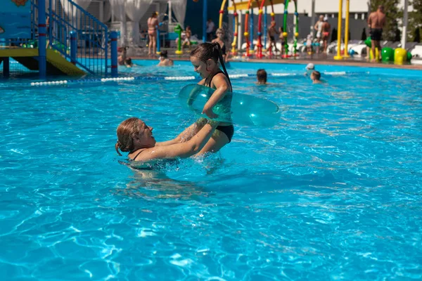 Abuela y nieta en la piscina. Una abuela joven lanza a una chica en un círculo inflable sobre la superficie del agua en la piscina del hotel en unas vacaciones de verano —  Fotos de Stock