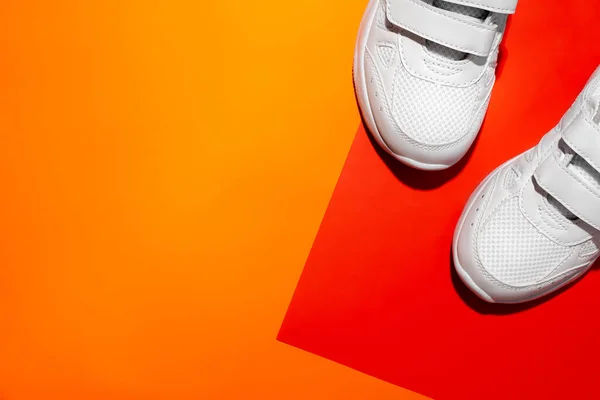 Plano poner las partes delanteras de dos zapatillas blancas sobre un papel geométrico fondo naranja y rojo con espacio de copia, playa y concepto de vacaciones —  Fotos de Stock