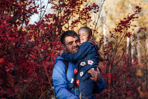 Chiudere felice ritratto di famiglia. felice padre tenere sorridente figlioletta in giacca blu su sfondo foresta autunno — Foto Stock