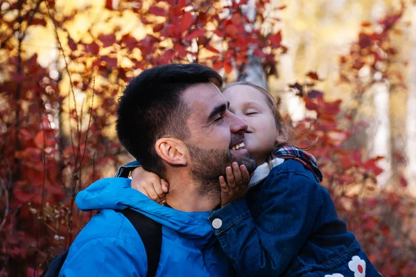 Primer plano retrato feliz padre. agradable niña beso feliz sonriente padre con pelo oscuro en otoño bosque fondo —  Fotos de Stock