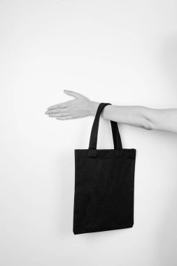 Eko-çanta tutan bir kadın. Beyaz izole zemin üzerinde geri dönüştürülmüş malzemelerden yapılmış, metin veya tasarım için alanı olan küçük siyah-beyaz eko-çanta modeli, sıfır atık kavramı