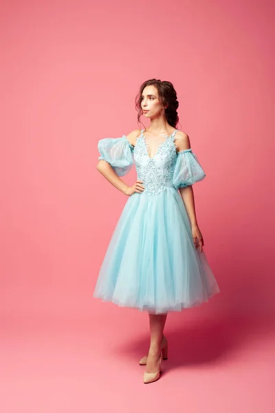 フルスカートとランタンスリーブ、ピンクの背景に隔離された青の夜のドレスでエレガントな若い女性の完全な長さの肖像画 — ストック写真