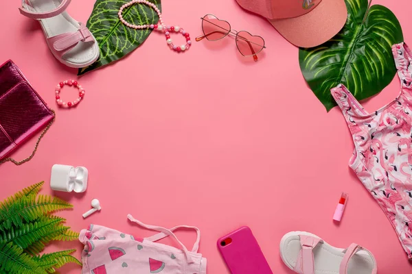 Plaj modası konsepti düz. Pembe arka planda yeşil yapraklı aksesuarlar ve elbiseler. Düz yatıyordu
