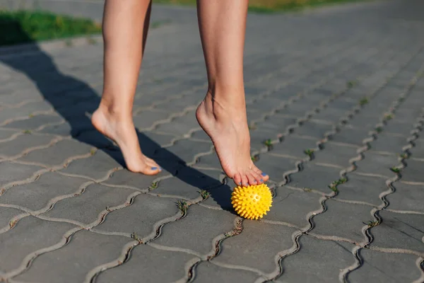 Primo piano di donne a piedi nudi in piedi su palla massaggiante a spillo per rilassarsi o fissare i piedi piatti su lastre di pavimentazione in parco in estate — Foto Stock