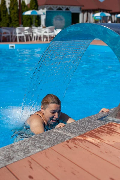 Die Frau ruht sich im Tropenresort aus. Wellness-Hydrotherapie des glücklichen Menschen unter dem Wasserfall im Sommerurlaub auf See — Stockfoto