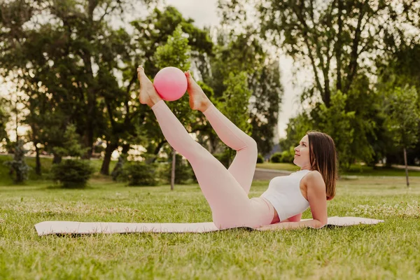 Mujer esbelta de cuerpo entero en pose superior rosa con bola de pilates, concepto de cuidado corporal y salud — Foto de Stock