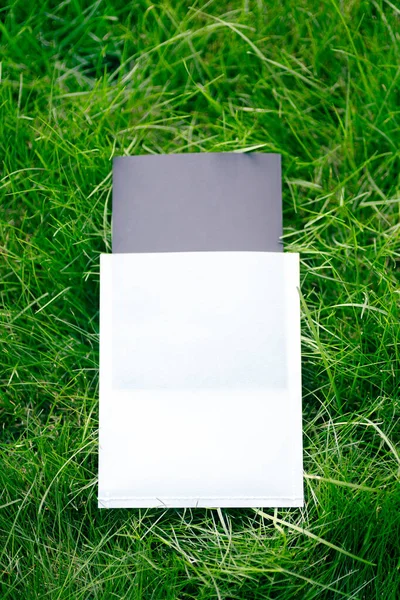 Draufsicht auf quadratischen Rahmen, ein kreatives Layout aus grünem Gras mit schwarz-weißer Hülle für Kleidungsanhänger. Das Formular für die Einladungskarte — Stockfoto