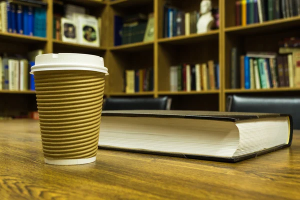 Paper cup of coffee and book on wooden table — Zdjęcie stockowe