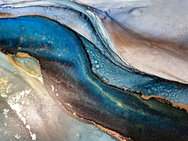 Abstract blue-green background with gold, beautiful smudges and stains made with alcohol ink and metallic pigment. Fragment of art with turquoise texture resembles sea, watercolor or aquarelle.