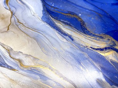 Abstract blue background with gold. Liquid abstraction with beautiful smudges and stains made with alcohol ink and golden paint. Blue fluid texture resembles sea, watercolor or aquarelle.