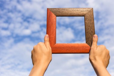 Resim çerçevesi üzerinde mavi gökyüzü izole kadın elinde