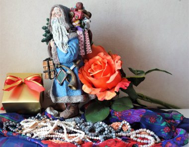 Noel Baba, hediye kutuları, çiçekler ve incilerle süslenmiş bir Noel hediyesiyle gelir..