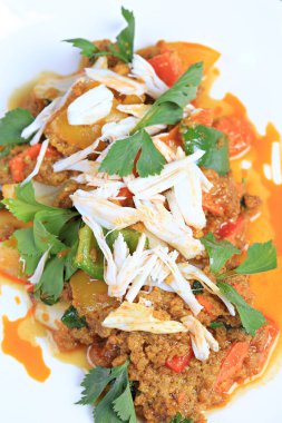 Köri tozu ile karıştırılmış yengeç eti, üstü beyaz tabakta haşlanmış yengeç etiyle süslenir. 